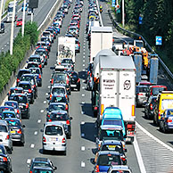 Cars in traffic jam on motorway during the summer holidays seen through magnifying glass held against illuminated terrestrial globe